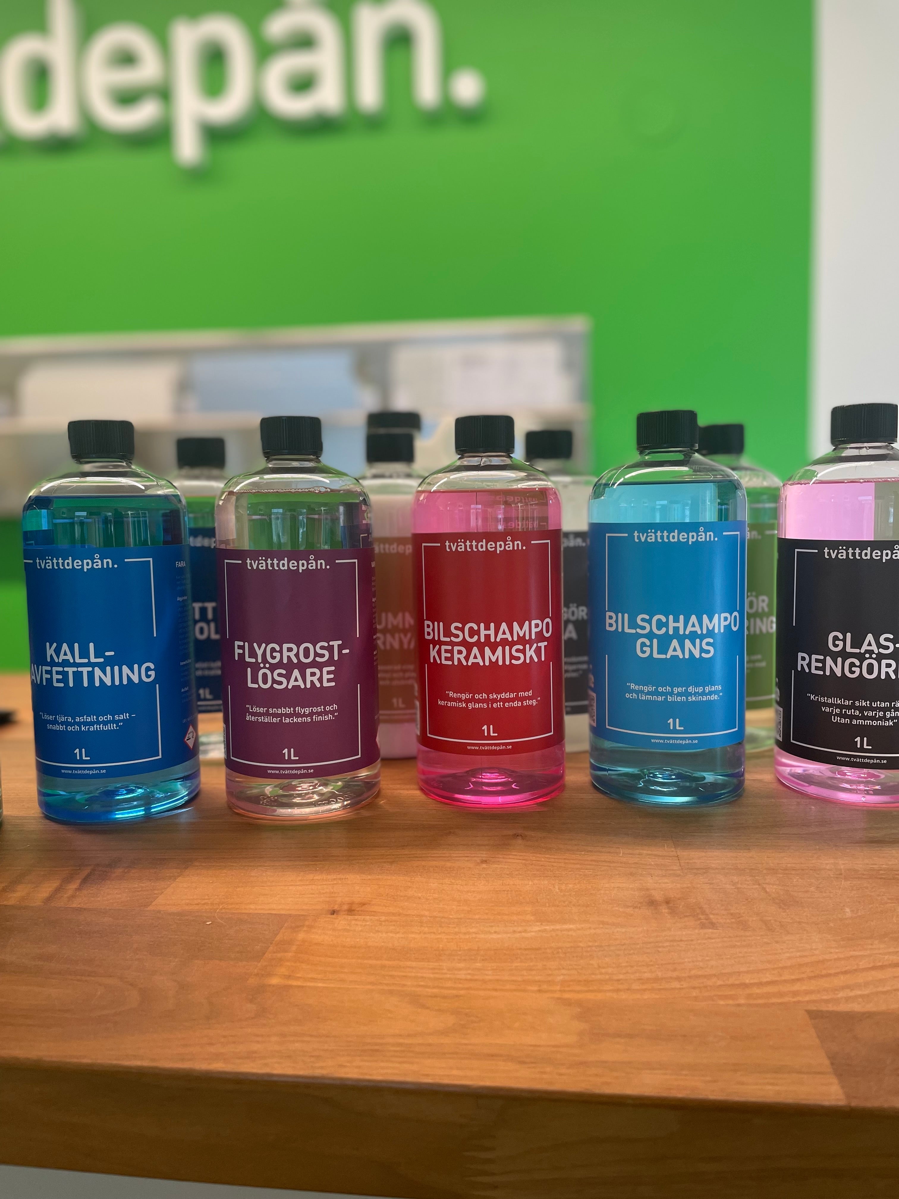 10 flaskor med 1 liters bilvårdskemi på en kunddisk av trä mot en grön bakgrund.